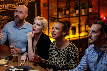 Group of friends watching tv in a cafe behind bar counter