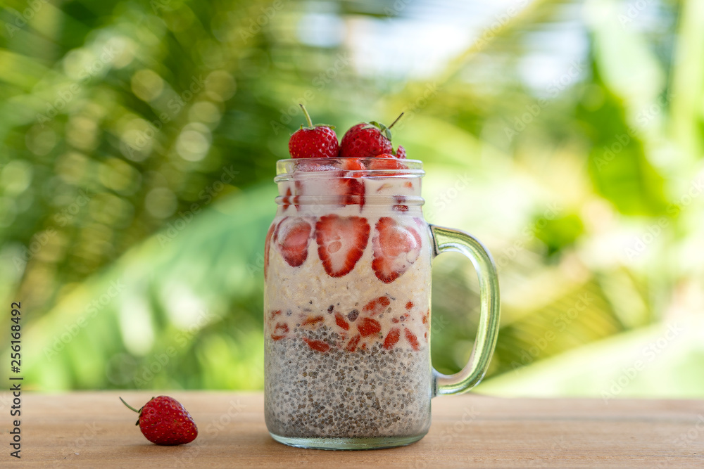 Wall mural almond milk chia pudding with fresh red strawberries, goji berries and oat flakes in a glass jar mug