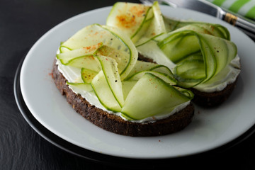 Cucumber sandwich. Healthy snack. Sandwich with cream cheese, cucumber, served on a plate. Symbolic image. Concept for a tasty and healthy meal. Close up.