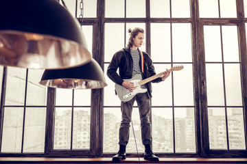 Rock musician standing on window sill and playing the guitar - Powered by Adobe