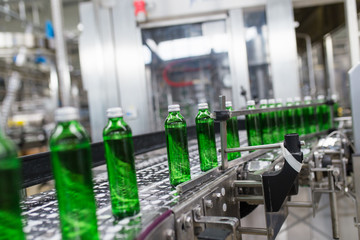 Bottling plant - Water bottling line for processing and bottling pure spring water into green glass bottles. Selective focus.