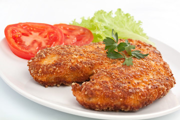 Deep fried chicken parmesan on a white plate with vegetables
