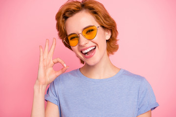 Close-up portrait of her she nice cute charming attractive lovely winsome cheerful girl wearing casual blue t-shirt yellow glasses showing ok-sign isolated over pink background