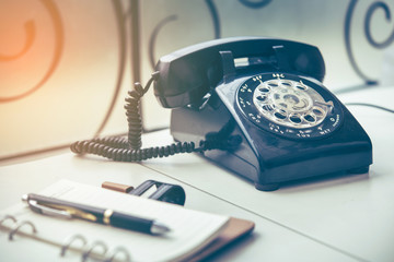 Ball point pen on notebook with old black phone background, retro style concept 