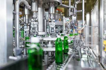 Bottling plant - Water bottling line for processing and bottling pure spring water into green glass bottles. Selective focus.