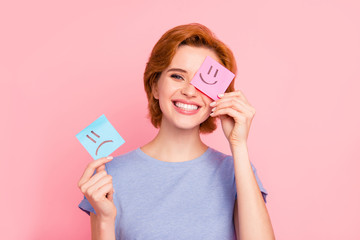 Close-up portrait of her she nice cute charming attractive cheerful girl wearing casual blue t-shirt holding in hands two draw notes positive good choice isolated on pink pastel background