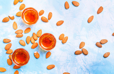 Almond liqueur with nuts on blue background, top view