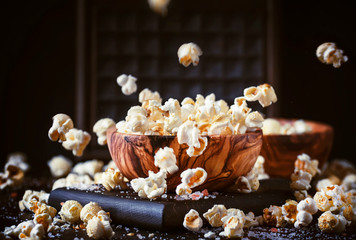 Salted popcorn in a wooden bowl, unhealthy food, dark wooden kitchen table background, selective...