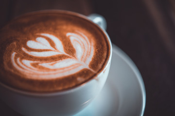 Latte arts coffe. White cup of hot coffee on wooden table. Cafe with barista art concept.