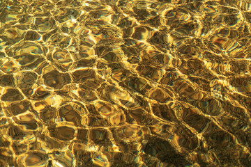 river water rippled water detail background with gold color from stone