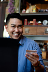 Making online bank transfer, man holds a credit card while entering data in laptop