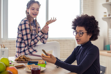 Attentive little male person spreading butter on toast