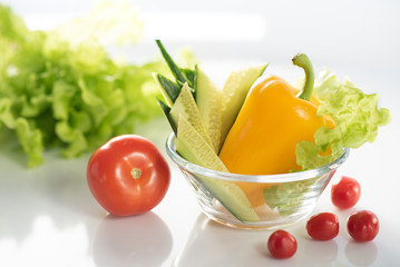 A set of fresh vegetables on a white plate, for the preparation of vegetable vegetarian salad. The background is white
