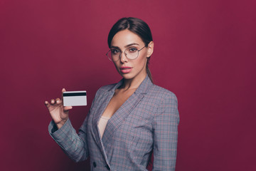 Naklejka premium Portrait of her she nice cute attractive lovely chic gorgeous confident lady gray checked jacket holding in hands showing plastic card balance budget isolated over maroon burgundy marsala background