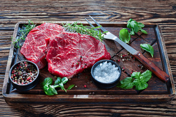 raw beef steaks on a wooden board