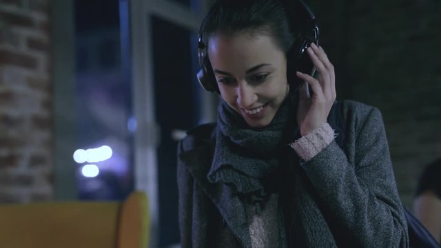 young pretty smiling woman is listening music in a big professional HI-FI headphones. listening to high-end sound on professional high-quality equipment