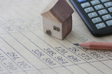 紙に書いた数字と鉛筆と計算機と家の模型