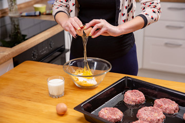 Closeup photo of woman breaking egg in glass bowl