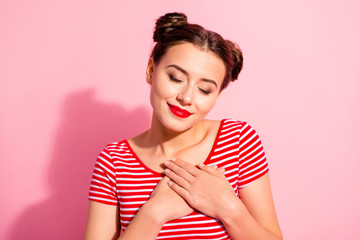 Close up photo beautiful amazing she her lady pretty hairdo two buns red pomade lips hold hands arms on heart eyes closed overjoyed wear casual striped red white t-shirt isolated pink background