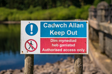 Sign: Keep out, authorised access only (Welsh & English), seen at the Alwen Reservoir, Conwy, Clwyd, Wales, UK - obrazy, fototapety, plakaty