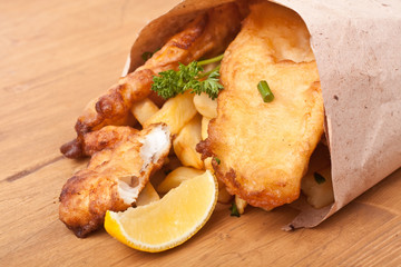 fish and chips wraped in paper on a wooden table