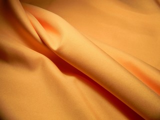 Peach colored plain cotton wavy fabric. Texture, background. template. Lightweight fabric for curtains or bed linen. Poplin, coarse calico, staple, satin, chintz. Folds. Textile. Material