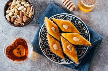 Baklava. Ramadan Dessert. Traditional Arabic dessert with nuts and honey, cup of tea on a concrete table. Top view