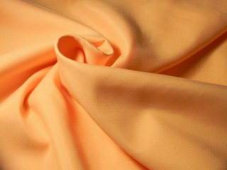 Peach colored plain cotton wavy fabric. Texture, background. template. Lightweight fabric for curtains or bed linen. Poplin, coarse calico, staple, satin, chintz. Folds. Textile. Material