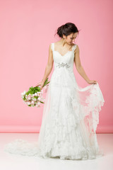 beautiful bride with wedding bouquet of pink tulips on pink background