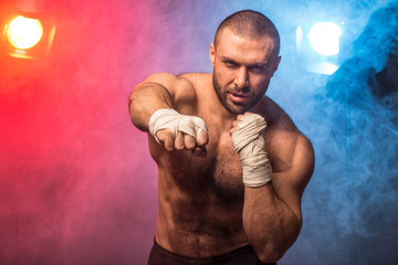 Young muscular boxing fighter training kicks. Kickboxer making a fighting exercise.