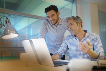 Male coworkers talking over ideas in modern office