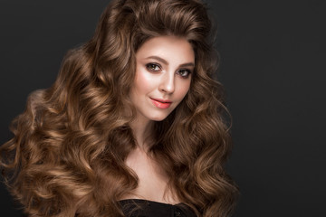 Fototapeta premium Beautiful brown-haired girl with a perfectly curls hair, and classic make-up. Beauty face.