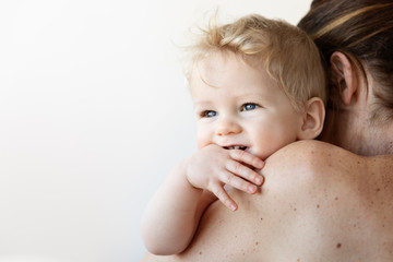 Smiling baby resting on mother's shoulder
