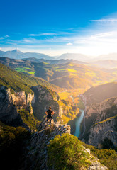 young man standing on top of cliff watching wonderful scenery in mountains during spring, colorful sunset in northern italy
