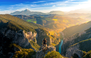young man standing on top of cliff watching wonderful scenery in mountains during spring, colorful sunset in northern italy