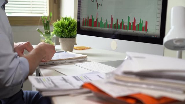 Business, people, paperwork and technology concept - Young Businessman Working on the desktop computer and with papers at office. Home finances, investment, economy, saving money or insurance.