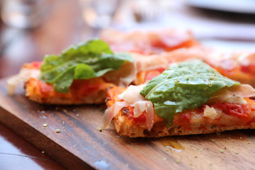 Pizza with parma ham salad rocket and parmesan on dark wooden background close up. Italian food
