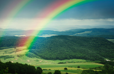 bright landscape with double rainbow above green hills and meadows, natural summer landscape