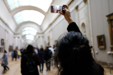 Frau im Museum mit ihrem Handy in der Hand