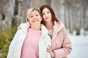 Fototapeta premium Mother and adult daughter walking in winter forest snowfall