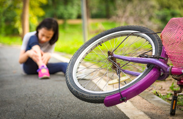 Asian little girl sitting down on the road with a slight sore leg pain due to a falling bicycle...