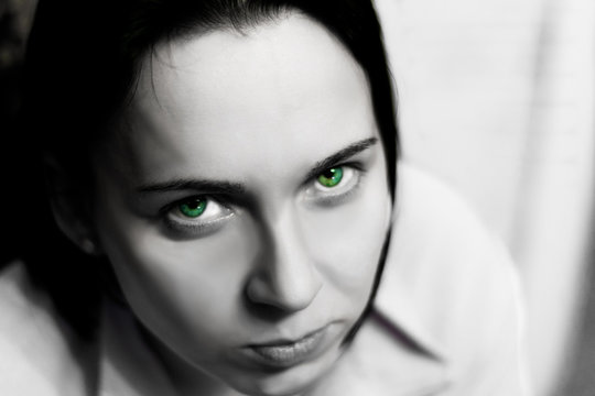 Creepy pale face of a girl with bright green eyes