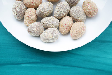 Chocolate egg candies in white bowl on blue background