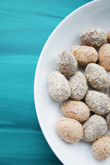Chocolate egg candies in white bowl on blue background