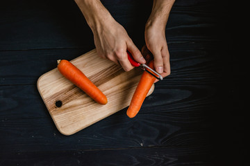 Peeling raw carrots on the rustic kitchen. Flat lay, top view. Cooking recipe preparation.