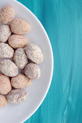 Chocolate egg candies in white bowl on blue background