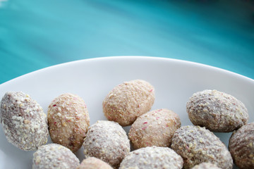 Chocolate egg candies in white bowl on blue background