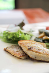 Sea bass fillet with grilled vegetables and salad on wooden table