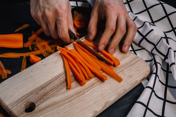 Cutting carrot on a wooden board. Julienne cut carrots.