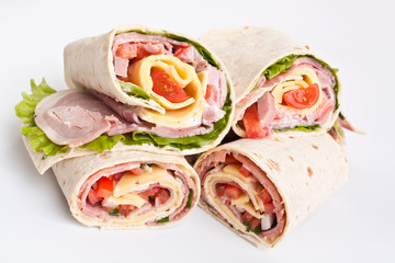 stack of wrapped tortilla sandwich rolls cut in half on white background